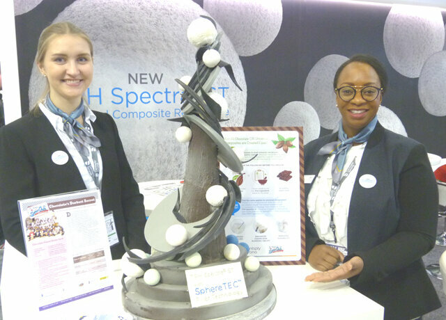 Corinna Prochner, left, and Lisia Malcolm in the Dentsply Sirona booth encourage everybody to check out the model of the SphereTEC Filler Technology that’s behind the company’s new TPH Spectra ST universal Composite Restorative. The model is sculpted entirely of chocolate.
