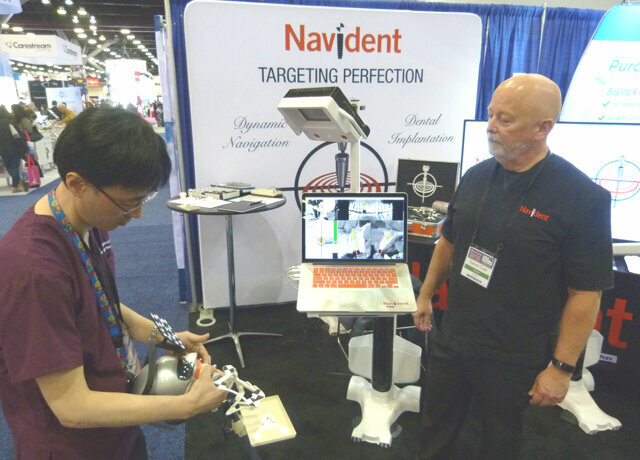 In the ClaroNav booth, Dr. Mark Kwon, left, demonstrates the dynamic surgical navigation system referred to as ‘Trace and Place’ as Darrell Cook of ClaroNav observes. The system was developed by ClaroNav.