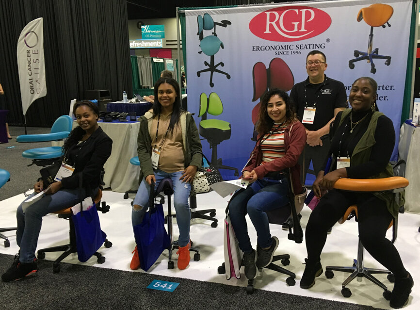 John Bonvini helps a group of attendees test out some of the latest ergonomic seating options available from RGP.