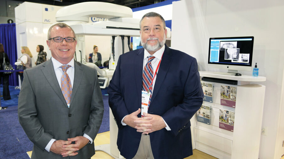 Andy Culver, left, and Mark Hofman stand in front of the Vantage pan-ceph system at the Midmark booth.