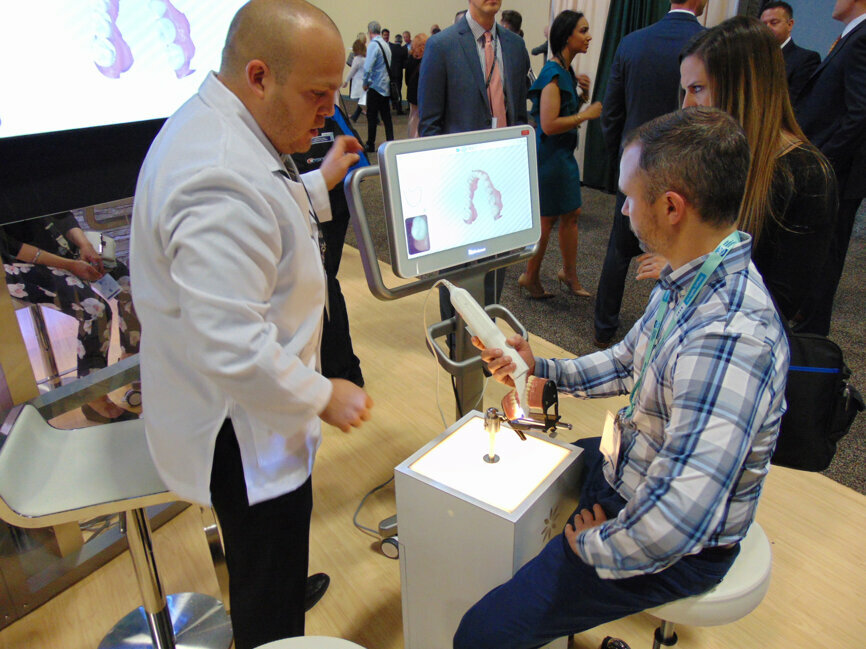 Carlos Nunez, left, of Invisalign iTero offers hands-on instruction to a meeting attendee during a one-on-one presentation.