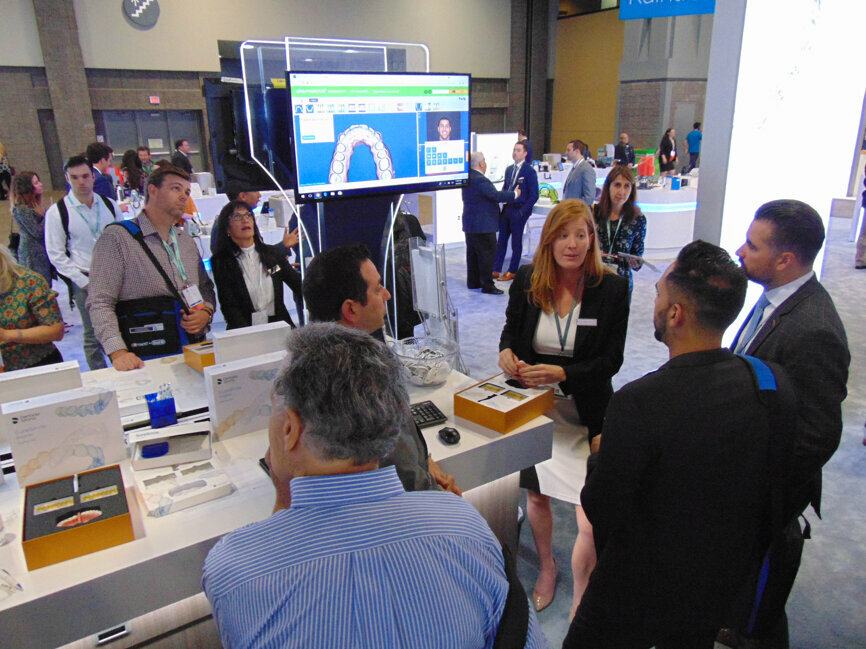 Meeting attendees get more information about the SureSmile aligner system at the Dentsply Sirona Orthodontics booth.