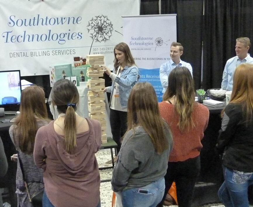 From Central Community College in Hastings, Neb., second-year dental-hygiene student Ally Kort starts on her next giant-Jenga move in Friday’s first-place playoff in the Southtowne Technologies booth. To the right from Southtowne Technologies are Seth Atherton and company founder Todd Sutton, DDS. Sutton, who also has two dental practices in Lander and Dubois, Wyo., after creating and fine-tuning a dental billing service for his practices, helps other practices benefit from his system. The company specializes in securing accounts receivable and communicating effectively with insurance companies to obtain maximum reimbursement.
