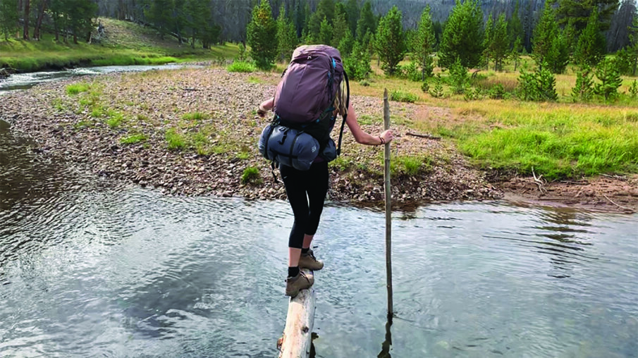 Ultradent's Katie Loyola balances on a downed log to cross a creek.