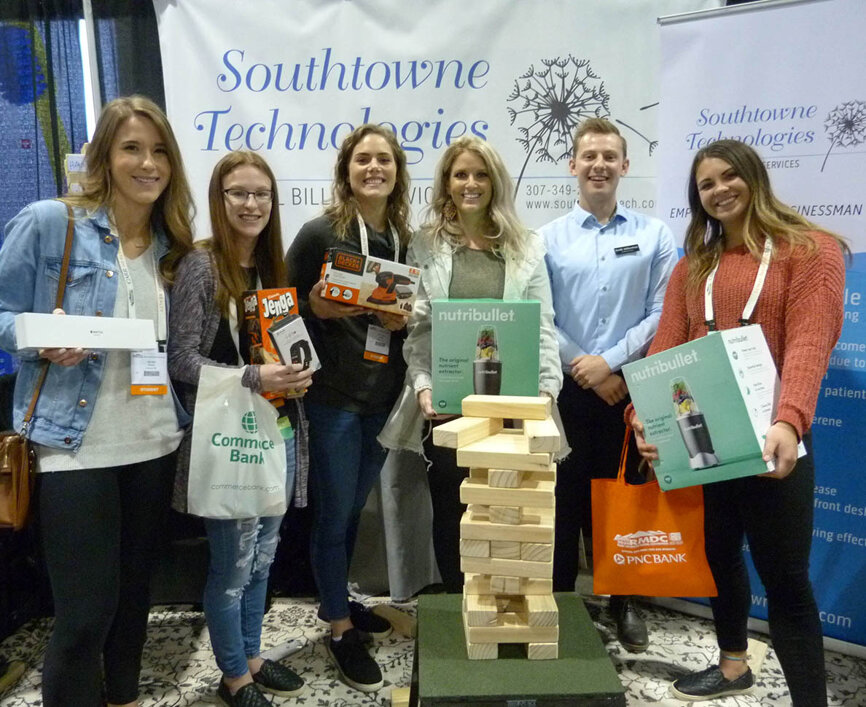 Displaying their Jenga-competition winnings in the Southtowne Technologies booth are from left, second-year dental-hygiene students from Nebraska Ally Kort, Morgan Schoening, Claire Snyder, Kelli Soucie (with Seth Atherton of Southtowne Technologies) and Hannah Tomes.