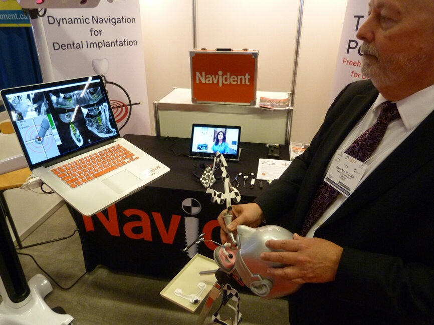 Darrell Cook demonstrates the Navident freehand guided surgery system in the ClaroNav booth.