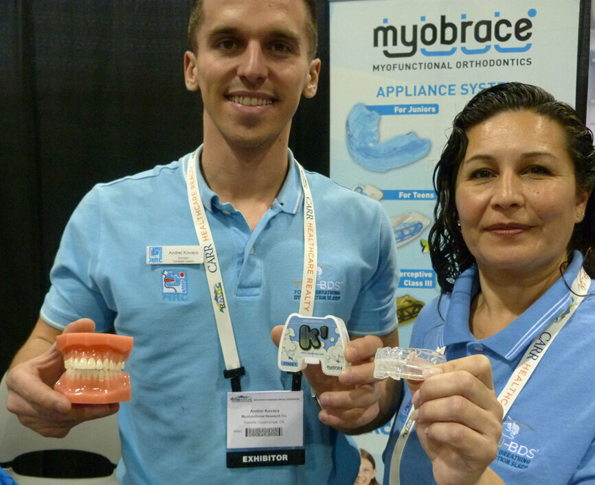 In the Myofunctional Research booth with examples of the Myobrace appliance system are Andrei Kovacs and Nancy Gomez.