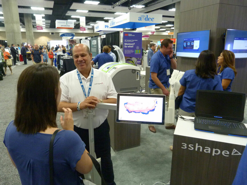 In the Henry Schein booth, Robert McCormick, 3Shape territory manager Carolinas, explains the 3Shape Trios Move wireless intraoral scanning technology to Melanie Vallejos, DDS, of Kahului, Hawaii. (Photo: Robert Selleck/DTA)