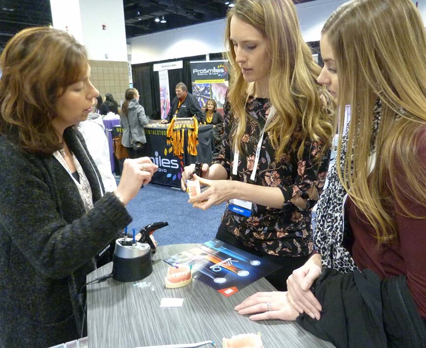 From left, in the “Bioclear Matrix Systems by Dr. David Clark” booth, Dee Dee Handy with Bioclear Matrix helps Dr. Katy McClure of Westminster, Colo., as Dr. Kristina Eidson, also of Westminster, looks on.
