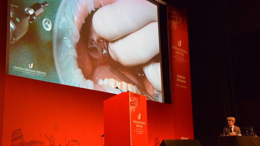 Moderator Dr Leonardo Muzzi looks on along and offers commentary to a captivated audience as Dr Hyun-Jun Jung performs a treatment of an edentulous maxilla in a guided surgery with immediate loading from another location in Rome. (Image: Dental Tribune International)