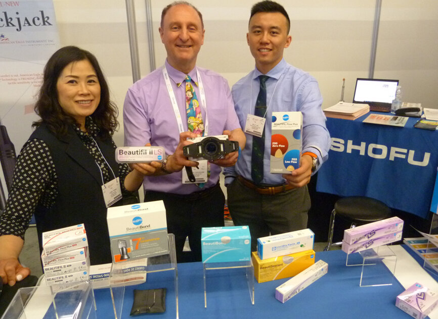 With various Shofu Dental products, from left, June Hong, David Goldshaw and Billy Ho in the Au-Shaw Dental booth.